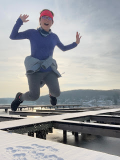 Me jumping on a snow-covered dock with the lake behind me.