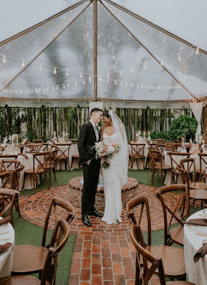 bride and groom standing under tent