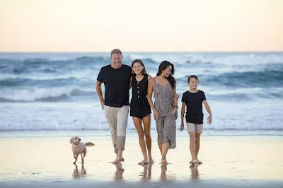 एक परिवार के सदस्य जिनमें पति पत्नी और उनके बच्चे साथ में एक कुत्ता है समुद्र के किनारे घूम रहे हैं