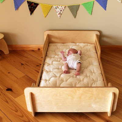 Infant sleeping on a floor bed with a wooden frame