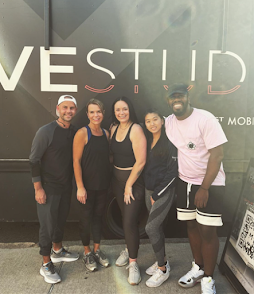 Staff and DJ with fitness instructor standing in front of mobile fitness studio