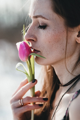 A Woman Smelling Flower and Wearing Different Types of Chains