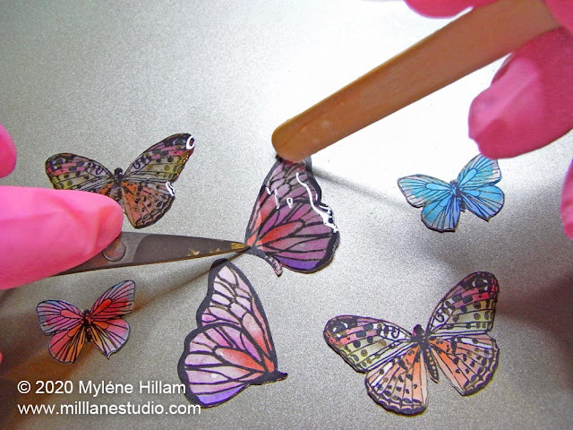 Painting resin onto the butterfly cutouts with a wooden stir stick