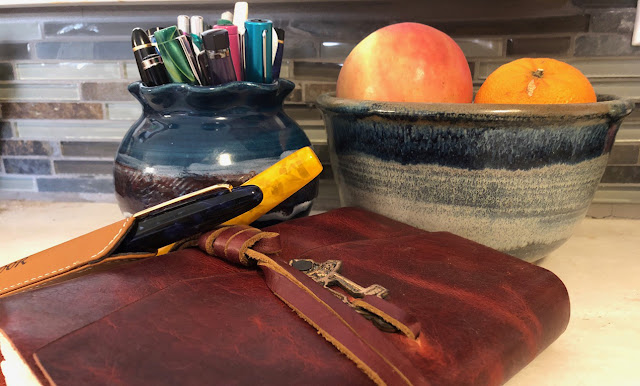 Fountain pens in a ceramic holder, and a handcrafted Journal.