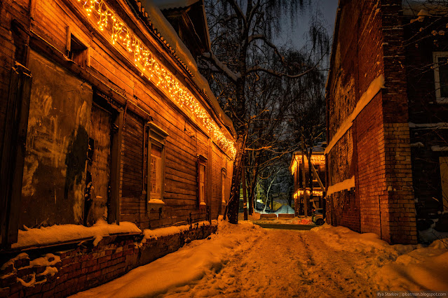 Переулок между деревянными домами в новогодней подсветке
