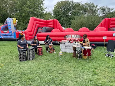 JMC employees sitting playing drums with performer at Kimball Farm