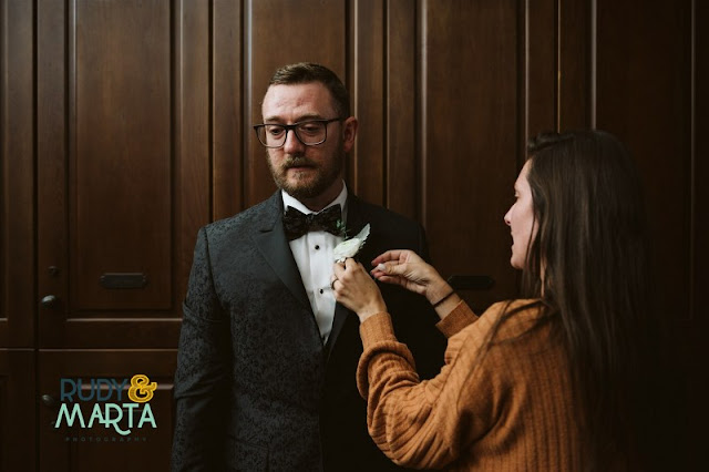 at last weddings coordinator putting boutonniere on groom