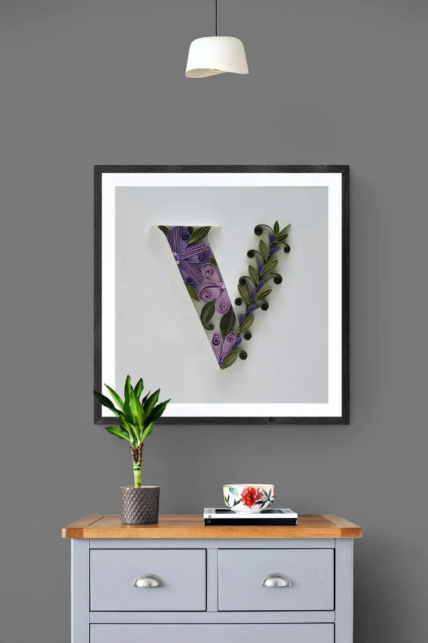 quilled letter V on-edge paper art displayed on wall