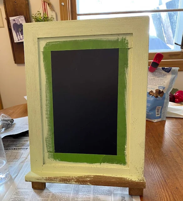 Photo of a chalkboard easel taped with Frog Tape being painted with Dixie Belle Chalk Paint.
