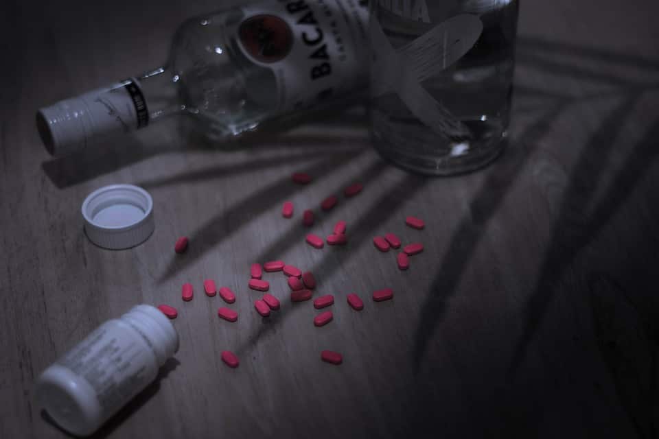 Bottle of alcohol, the shadow of a leaf, and some spilled pills