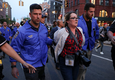 color photograph of NYC Policeman escorting handcuffed photojournalist Stephanie Keith following her arrest at a protes on May 8, 2023