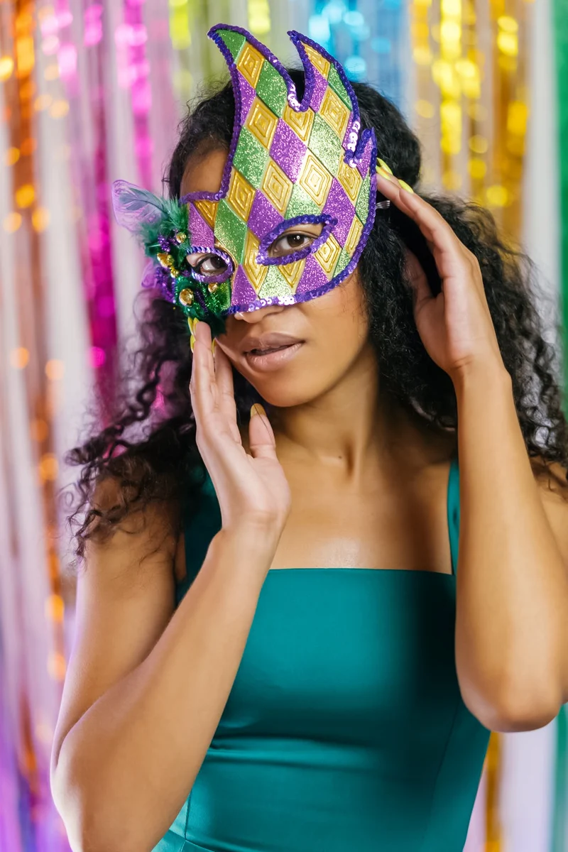 beautiful woman is holding carnival mardi gras mask to her face