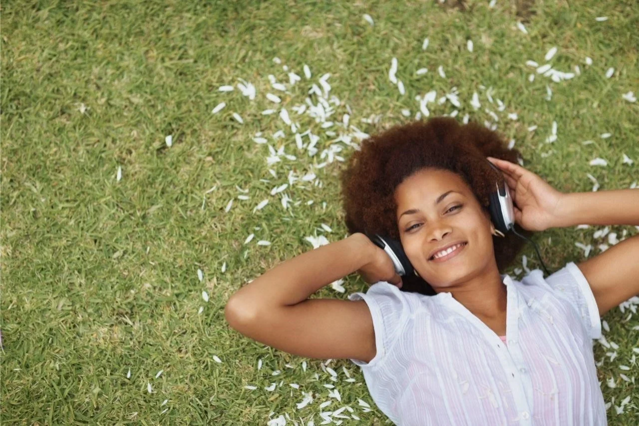 Jovem descansa no prazer de um jardim florido e com música