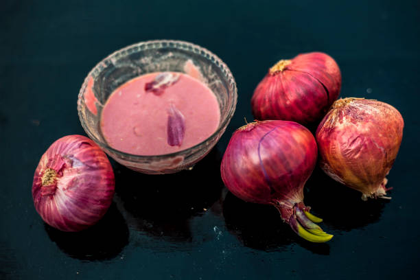 Glass bowl with onion pulp and raw onions, a natural remedy for hair loss.