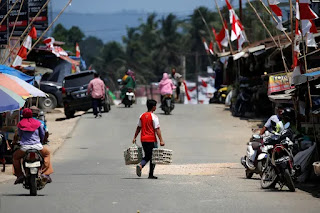Seorang pria membawa telur saat menyeberang jalan di Pasar Sepaku di Kabupaten Penajam Paser Utara, Kalimantan Timur