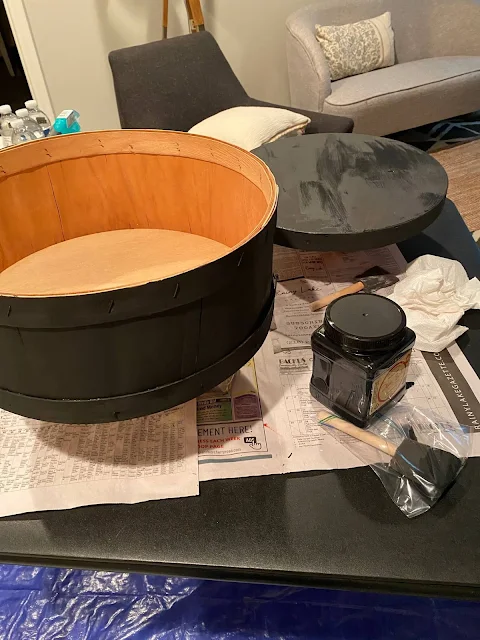 Photo of a round wooden box being painted black.