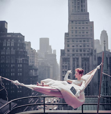 color photograph of dancer Gwen Verdon lounging in a hammock on a balcony overlooking the New York skyline in 1953