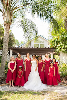 bride in white gown with bridesmaids in red