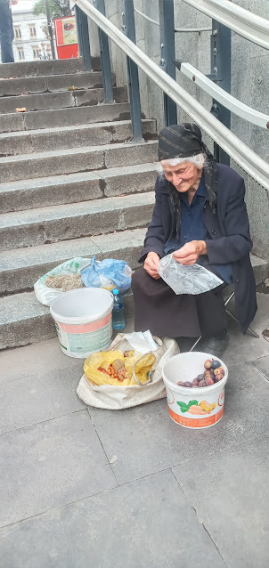 A aged women selling berries on the steps of Underground passage at Liberty Square.