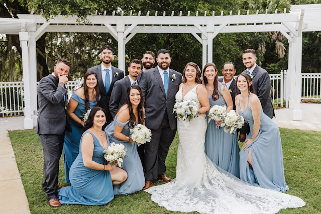 bride and groom smiling with bridal party in blue and grey