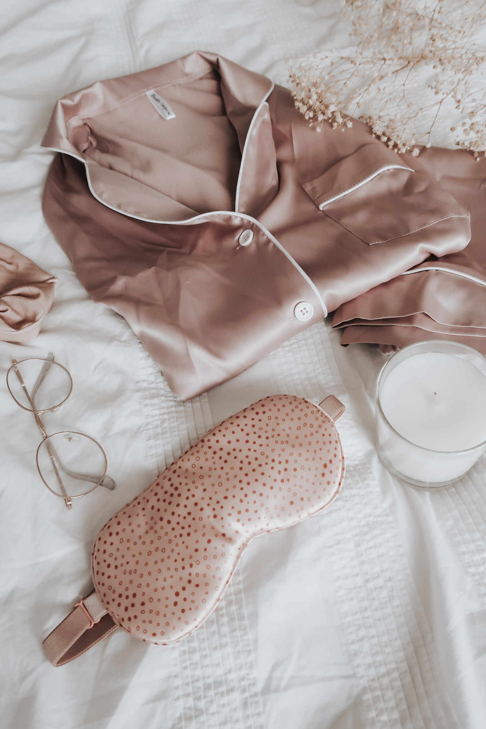 IDentity lingerie pink silk pyjamas on a white bed.