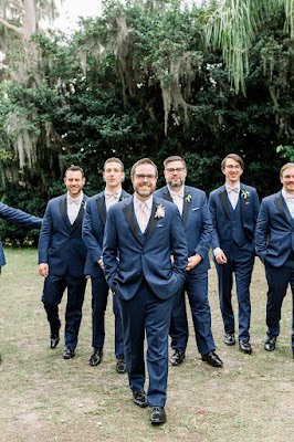 groom in blue suit walking with groomsmen