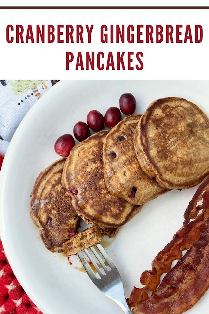 Plate of cranberry gingerbread pancakes with a fork, bacon, and fresh cranberries.