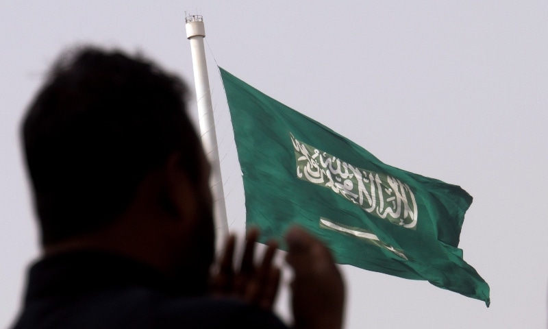 A man prays at an open air makeshift mosque in front of a giant Saudi Flag in Jeddah on June 21, 2017. — AP