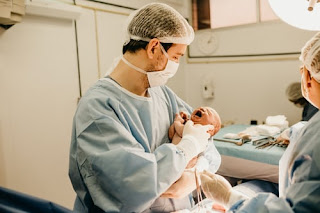 A doctor carrying a baby, a nurse standing