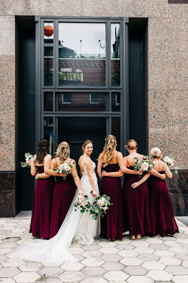 bride smiling and hugging girls in burgundy dresses