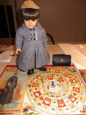 girl doll in tan baseball cap and gray and white tweed coat stands in the middle of a colorful puzzle game board depicting Nellie Bly's trip around the World