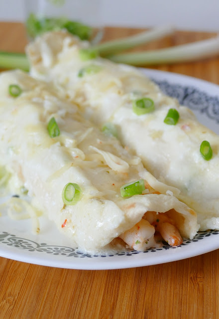 Enchiladas on a white plate with wooden background.