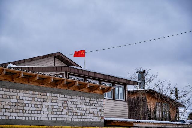 Красный флаг с серпом и молотом над частным домом