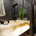 Banheiro com cara de lavabo decorado com seixos pretos, bancada em ônix e metais dourados!