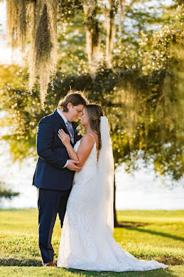 bride and groom in front of lake with trees