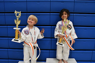 Two martial arts preschoolers winning awards at a Taekwondo tournament