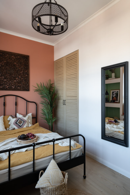 Dormitorio pequeño con cama de hierro y pared rosa