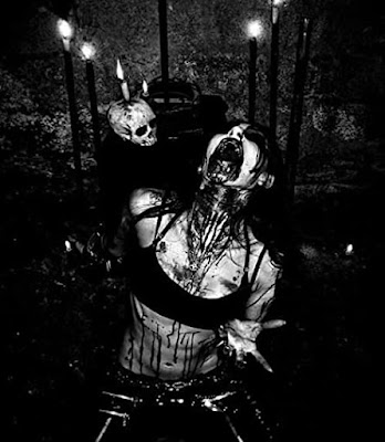 Vicious back and white photo of a vampire female in full mouth snarl blood dripping from her mouth with lit candles and skull in the background