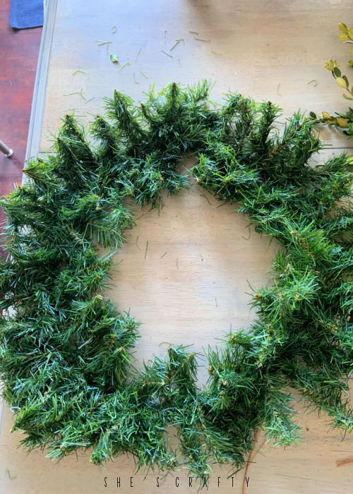 Inexpensive Pine Wreath flattened on a table.