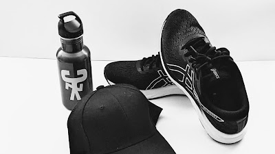 A cap, water bottle and ASICS runners ready for a big walk.