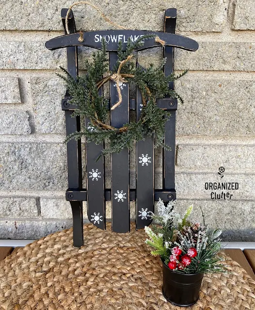 Photo of a small sled painted black with snowflake stenciling.