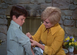 Carol Brady pins the sleeve of an oversized shirt Bobby is wearing.