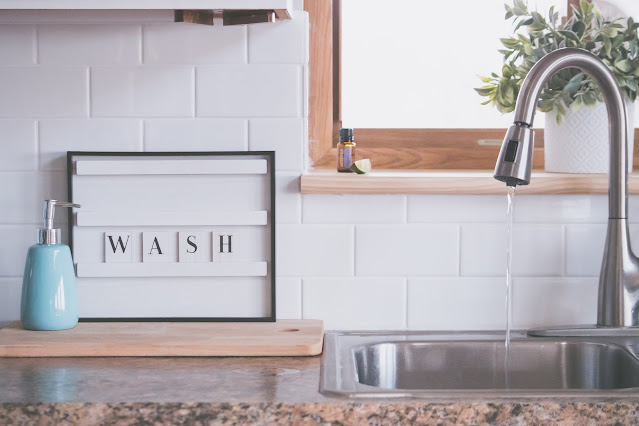 A wash area featuring a sink, liquid soap pump, and a signage with the word "WASH" spelled out.