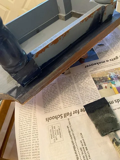 Photo of a small wooden stool being painted navy blue.