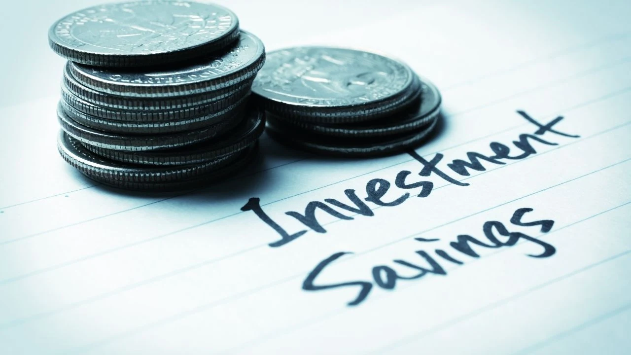 Written words investment and savings next to two stacks of US dollar quarter coins.