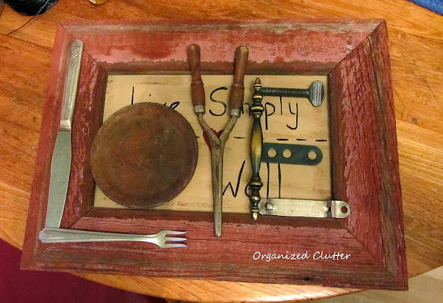 Photo of random junk laid out on a barnwood framed picture to form the word love.