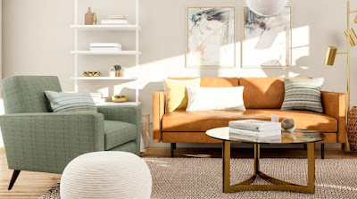 An orage sofa, sage green armchair, and round coffee table on beige rugs