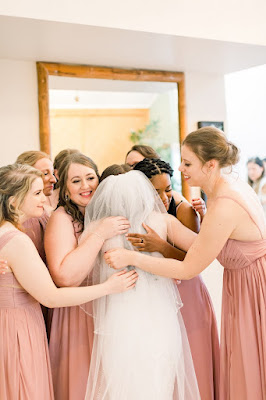 bridesmaids in pink dresses hugging bride