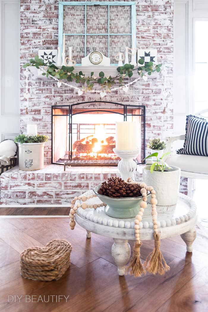 neutral winter decor painted fireplace, vintage crock, wood bead garland, greenery