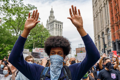 Close up photograph of African American women with bandanna covering her face and arm raise in protest march after the murder of George Floyd, Manhattan, New York,, June 2, 2020